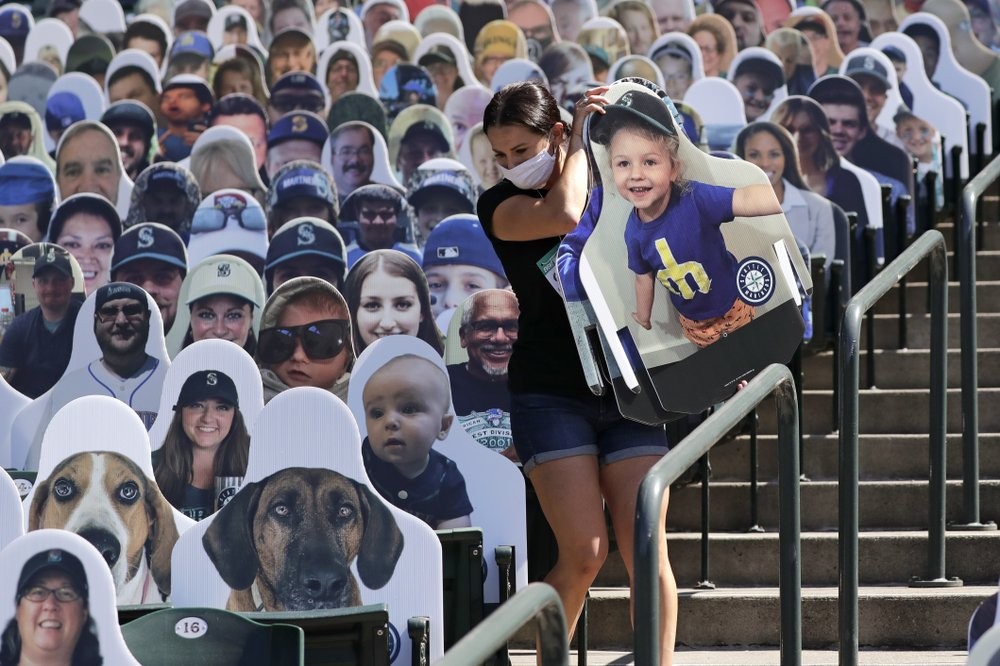 Seattle Mariners worker Lindsay Garza carries cutouts of fans to place in seats at the team's ballpark as part of the "Mariners Seat Fleet" in Seattle. (AP Photo/Elaine Thompson)